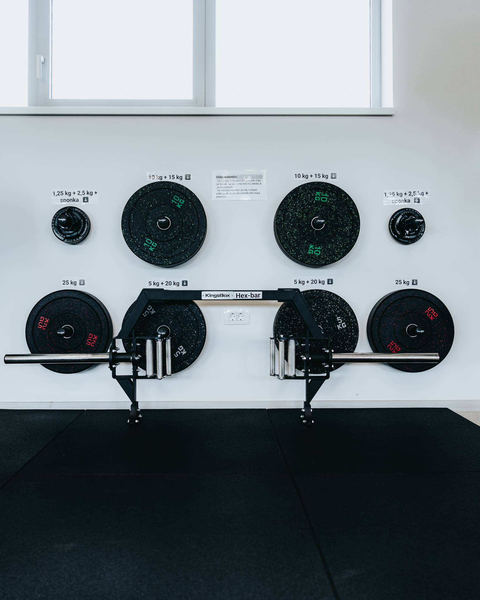 Utežne plošče bumper plates na stojalu ob olimpijski platformi